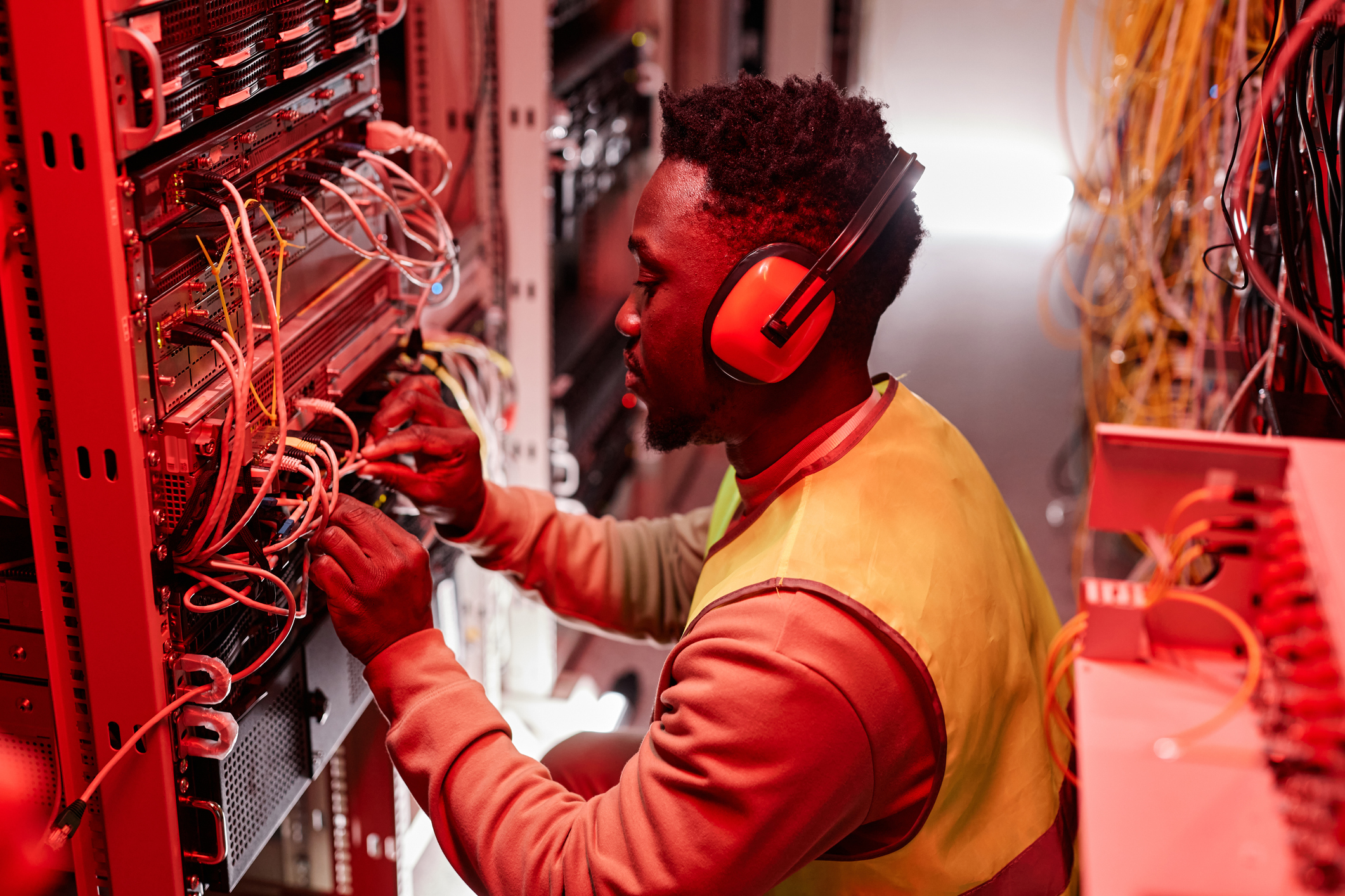 Technician setting up network in server room red neon lights