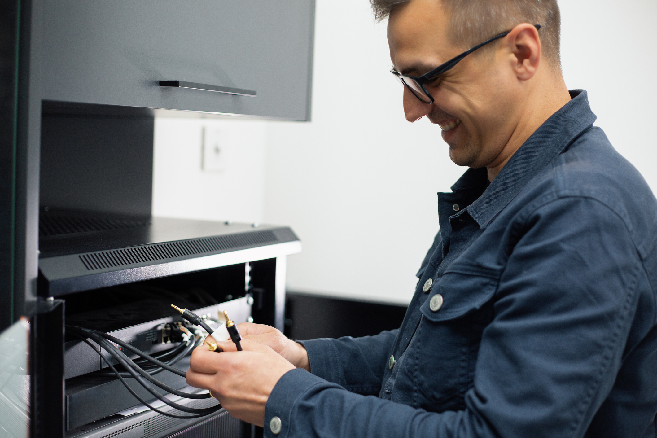 Technician connecting audio cables to stereo receiver in living room